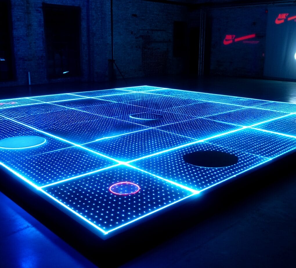 A large, illuminated grid with blue LED lights and circles on its surface, set indoors with brick walls and dim lighting.